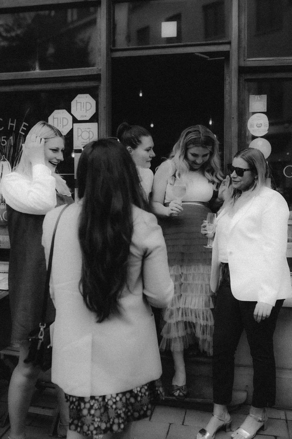 Guests laughing together with drinks outside the Kitchen 151 window