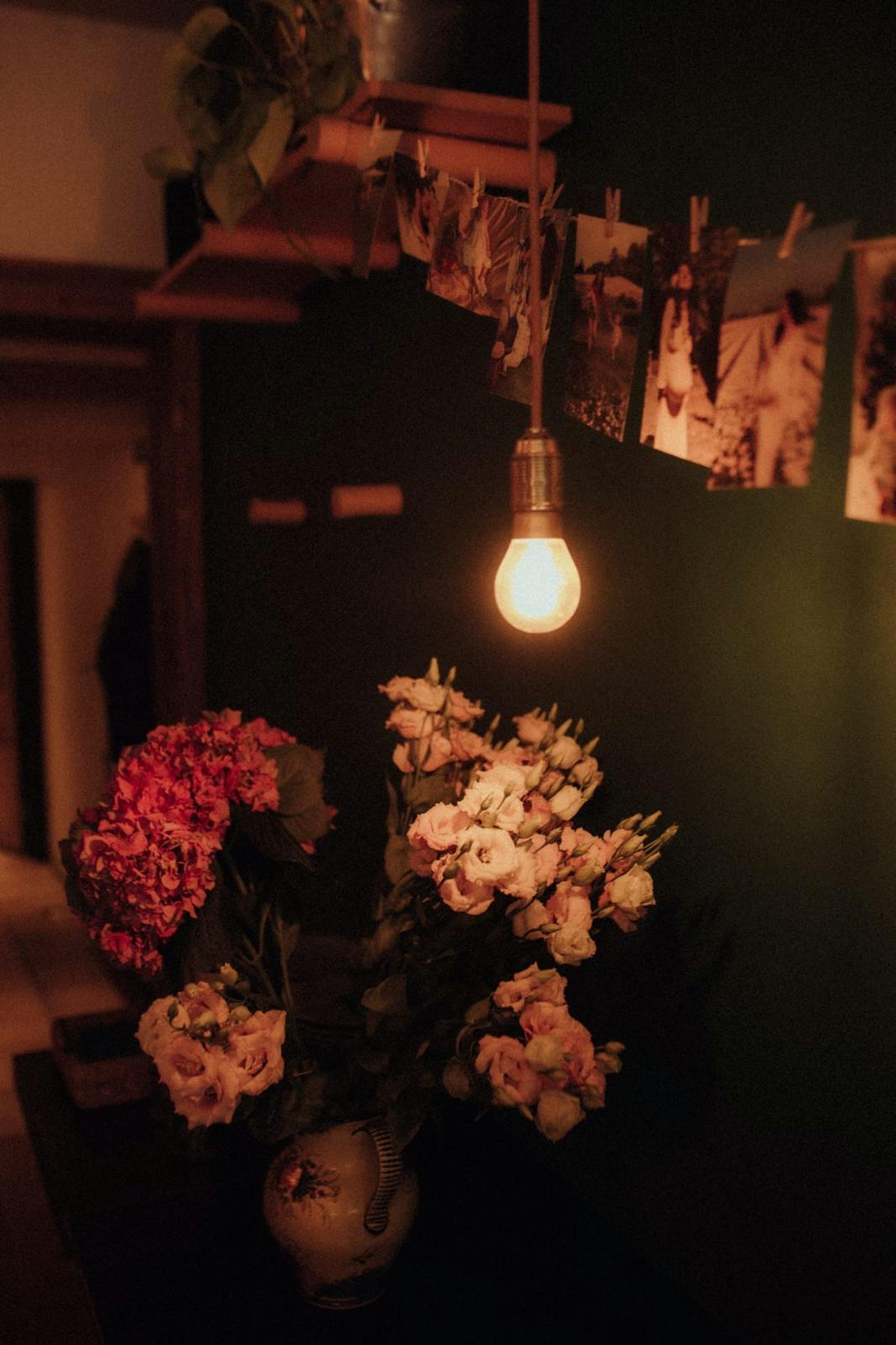 Warm bulb glowing above flowers and photos pegged on a line at Kitchen 151