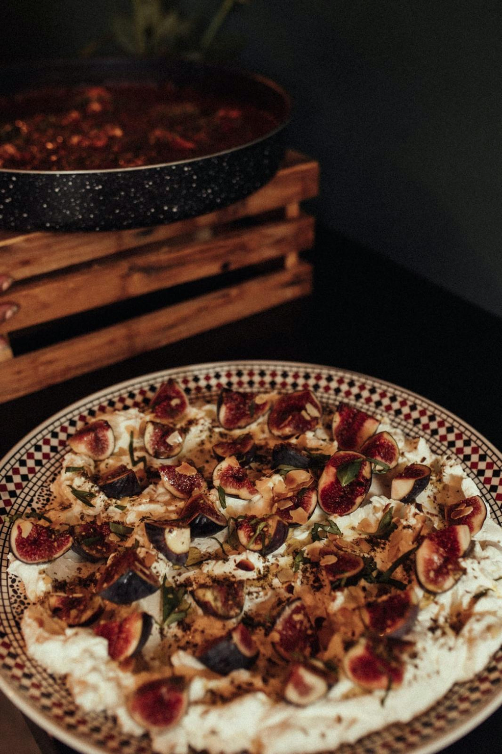Labneh topped with fresh figs, herbs and almonds on a patterned platter