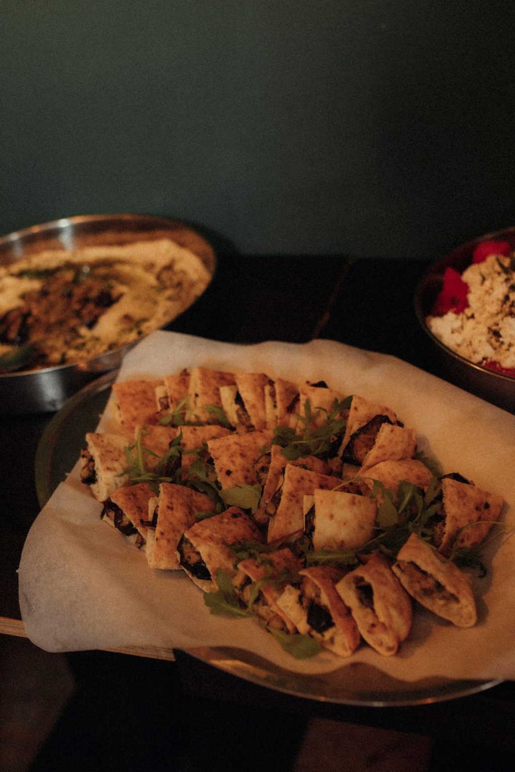 Platter of stuffed flatbread wraps with arugula and dips
