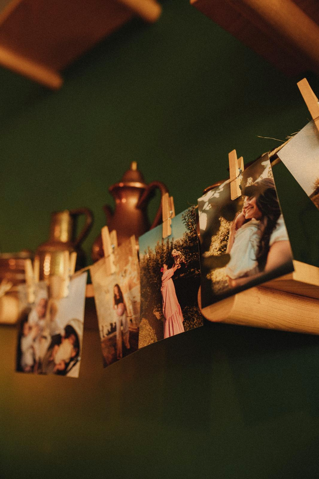 Printed photos pegged on a line against a deep green wall