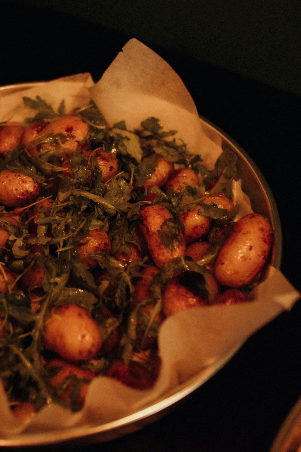 Roasted baby potatoes tossed with arugula in a serving tray