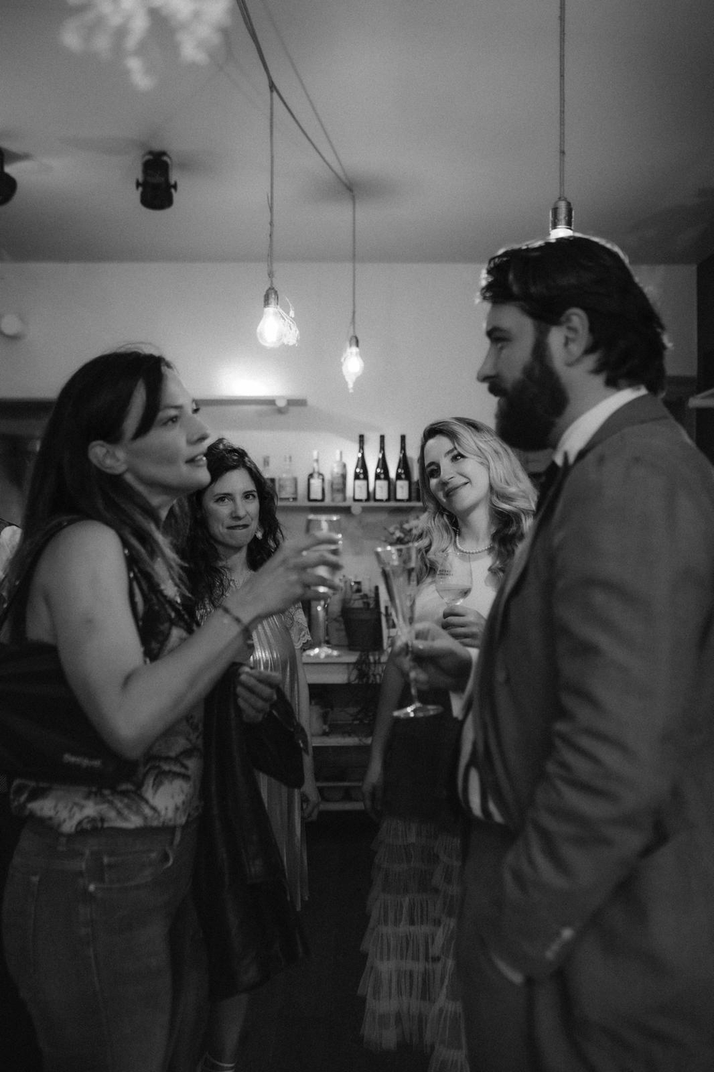 Guests chatting over drinks at a private dinner, in black and white